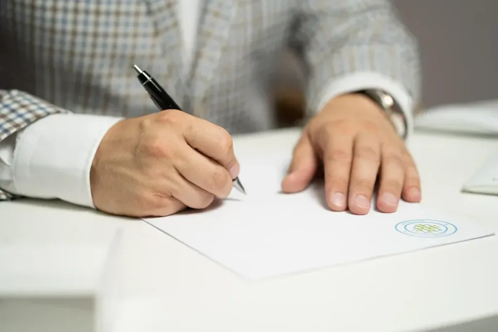 Mężczyzna podpisuje umowę przy biurku: umowa z klubem albo własna firma trenera